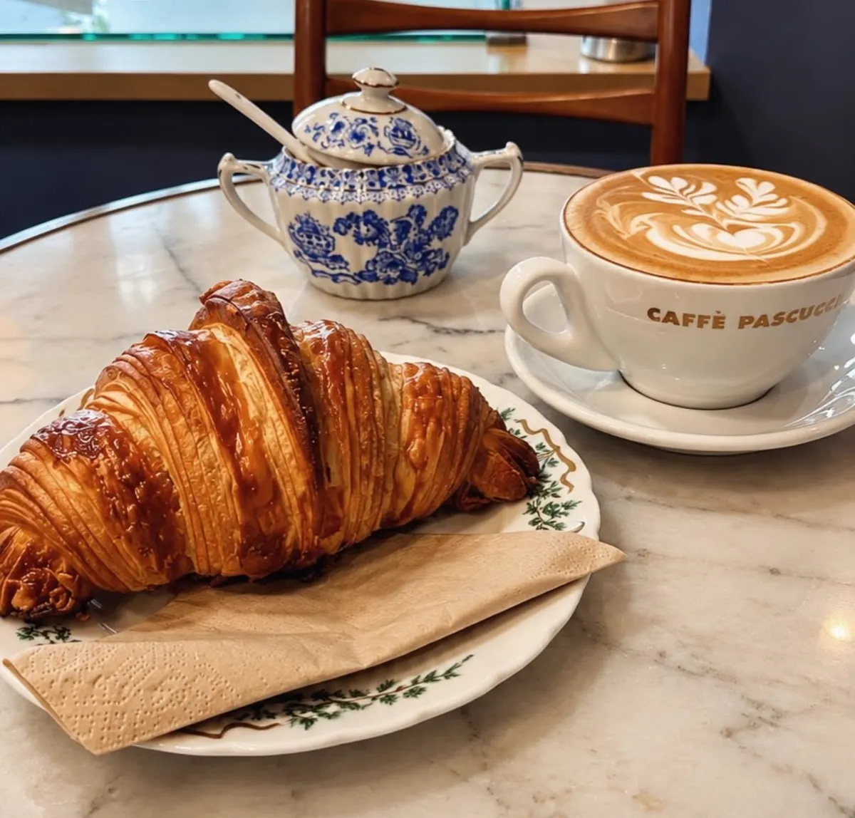 Ein Croissant mit Latte Art auf dem Marmortisch