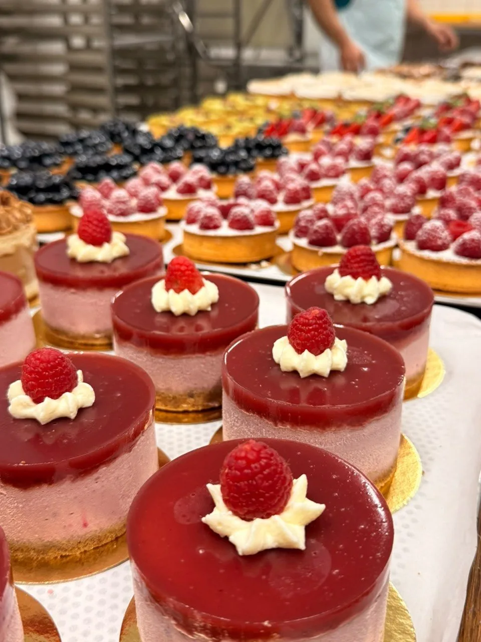 Himbeer-Mousse-Törtchen, dahinter Reihen von Tartes